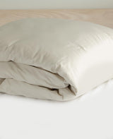 Dune-toned cotton percale duvet cover folded on a bed