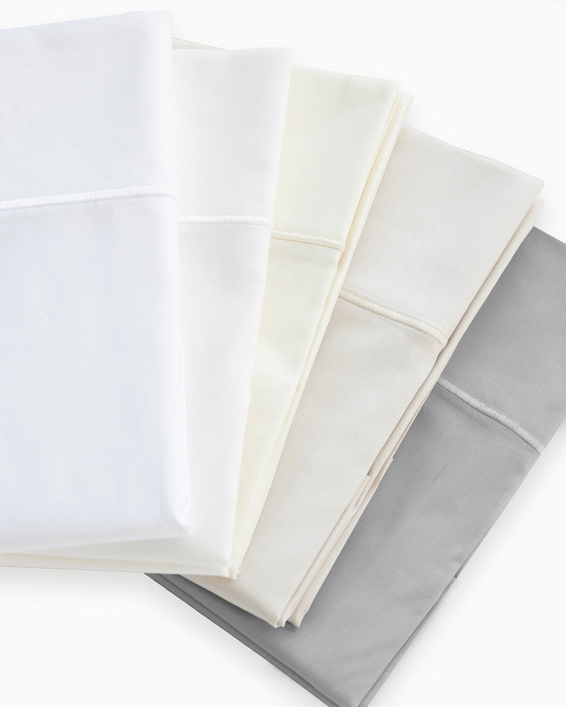 Stack of cotton percale sheets fanned across a flat surface