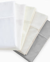Stack of cotton percale sheets fanned across a flat surface